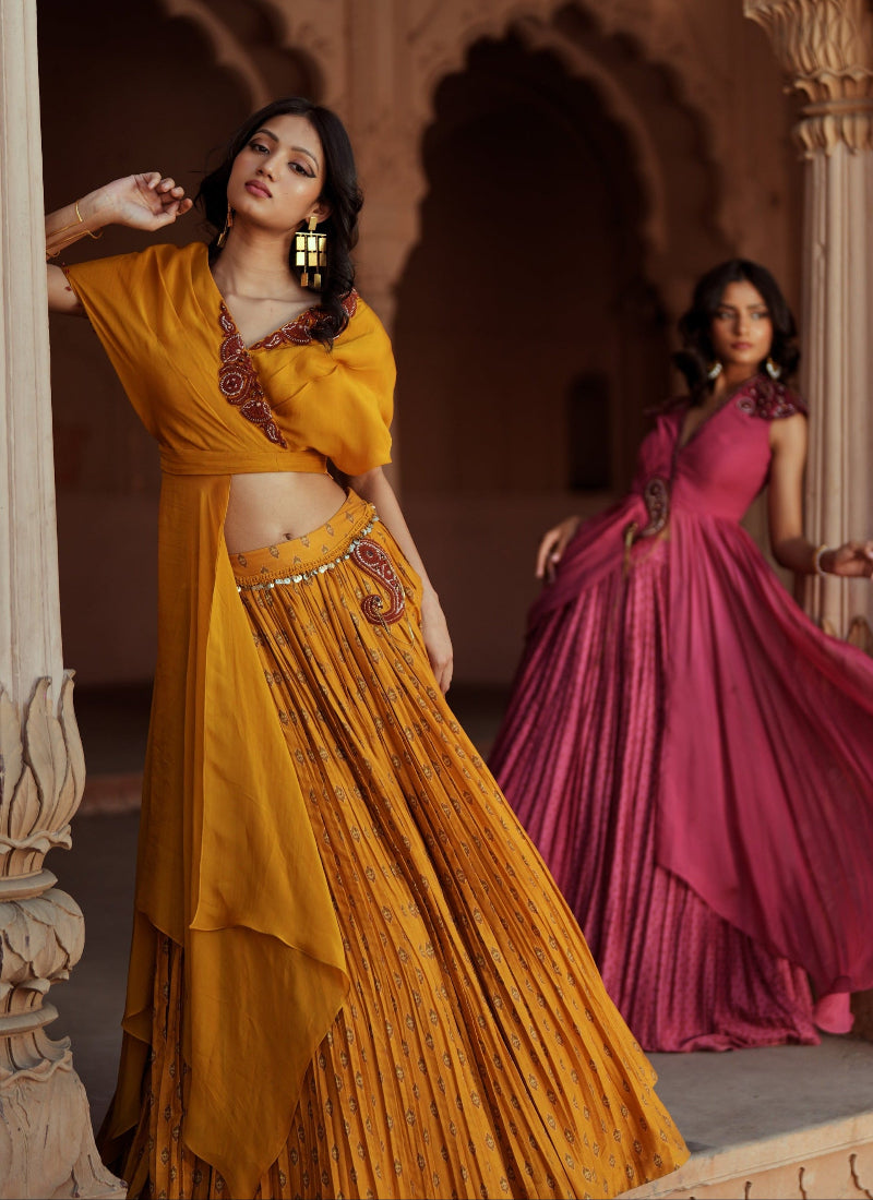Two women in traditional dresses standing against mughal walls