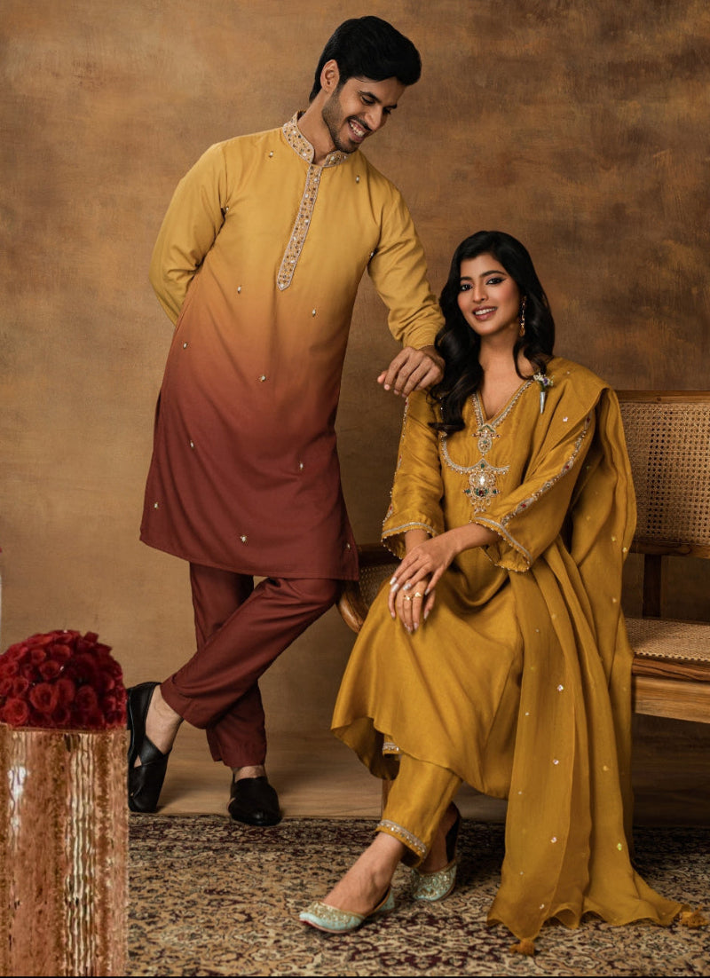 Man and woman in traditional attire posing against a warm-toned background